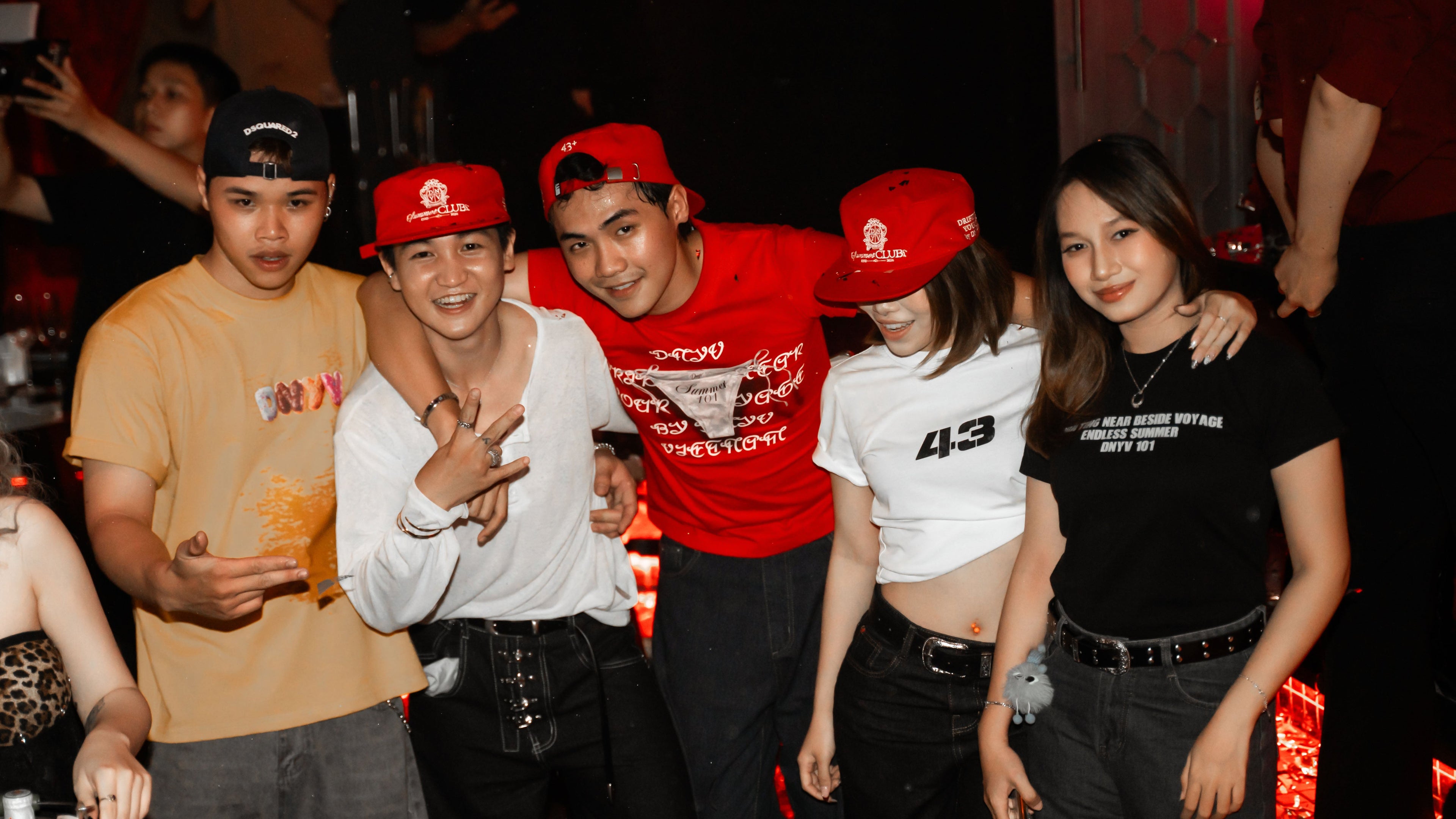 Group of people wearing red caps posing together at a party.
